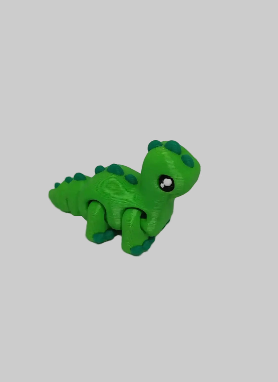 Close-up of articulated brontosaurus dinosaur toy. Green dinosaur toy figure on a light gray background