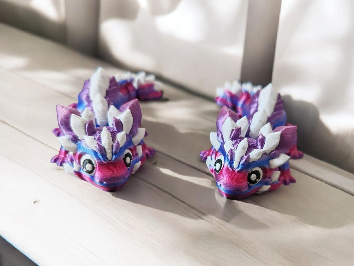 Two colorful dragon-shaped toys on a wooden surface with a blurred background